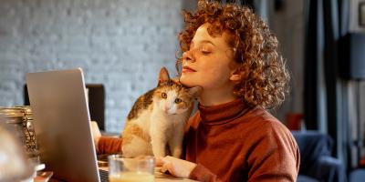 Young woman with pet cat using laptop