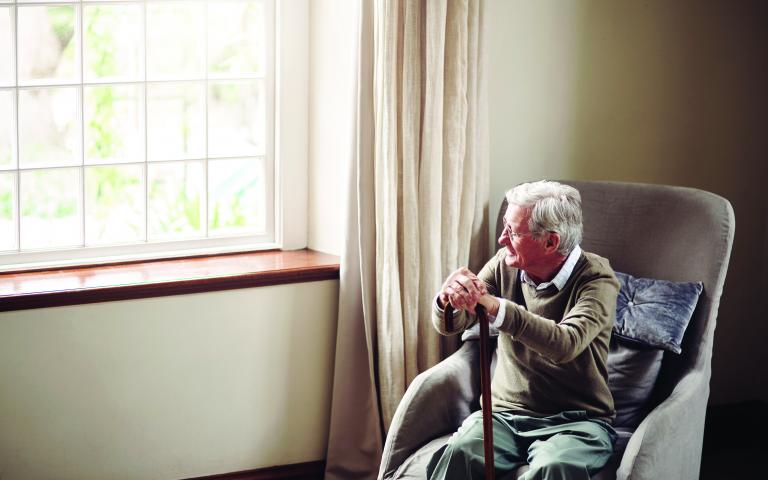 Elderly man sitting in chair and looking out the window