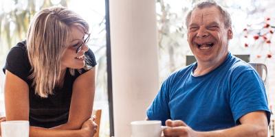 Person with disability smiling next to carer