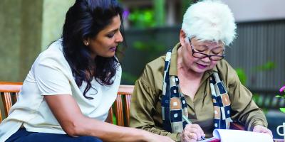 Younger woman showing document to older woman who is signing it