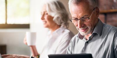 Older couple look at tablet and having coffee